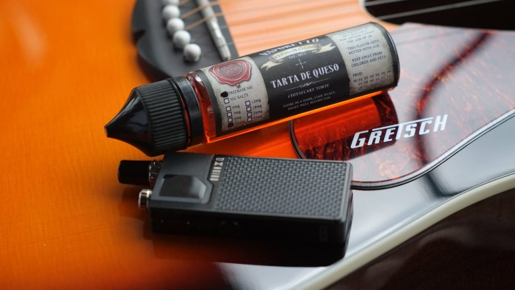 The Art of Drawing Readers In: Your attractive post title goes here Close-up shot of a vape liquid and device on a Gretsch guitar, blending music and modern technology.