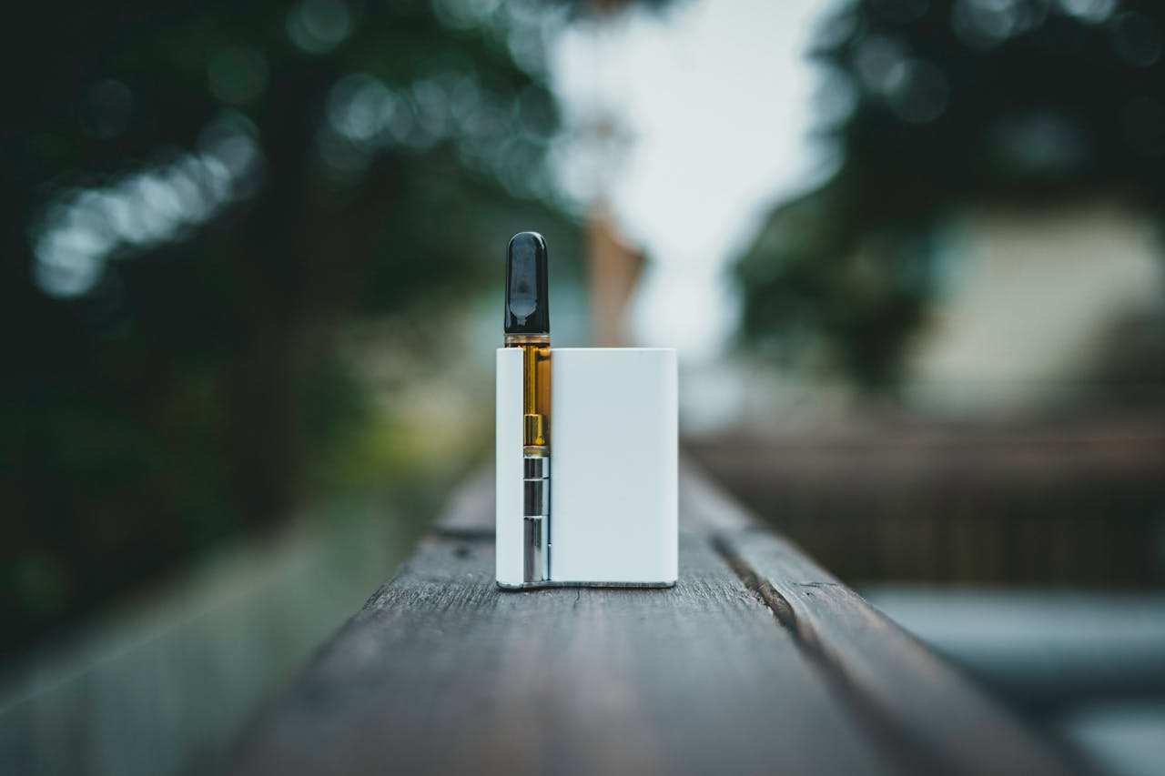 our-story-01 A sleek vape device resting on a wooden surface outdoors in natural light.